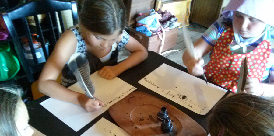 kids writing pioneer letters with quill pen and ink