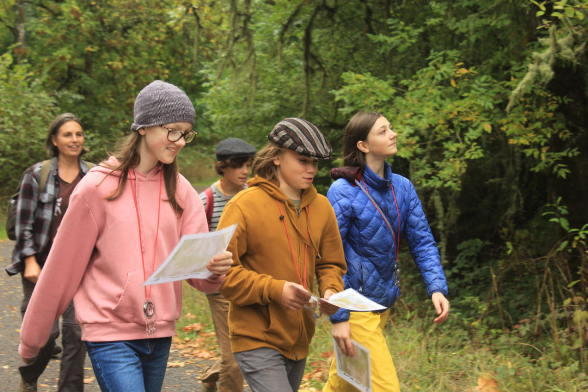 Jess with kids working on map and compass on trail